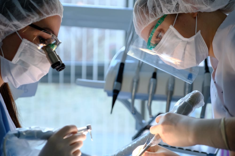 dental oral surgery on patient conducted by two dentists